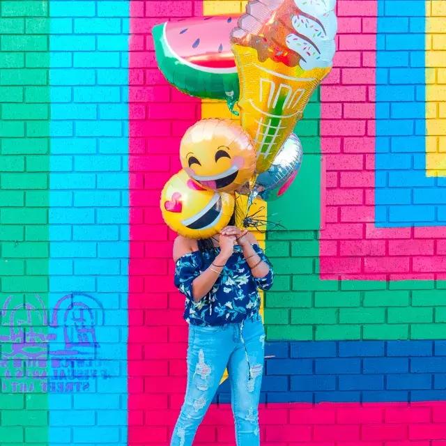 一个女孩在一幅彩色壁画前用气球庆祝她的生日。.